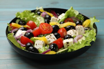 Delicious fresh Greek salad on light blue wooden table, closeup