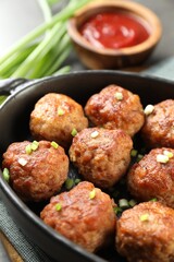 Tasty meatballs with green onion in baking dish on table, closeup