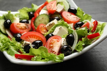 Delicious fresh Greek salad on black table, closeup