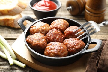 Tasty meatballs in baking dish served on wooden table, closeup