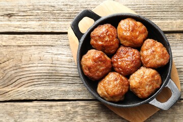 Tasty meatballs in baking dish on wooden table, top view. Space for text