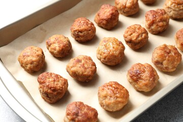 Many delicious meatballs in baking dish on grey textured table, closeup