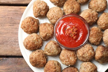 Delicious meatballs with ketchup and spices on wooden table, top view