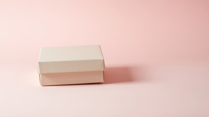 A closed pale pink gift box sits on a pale pink background