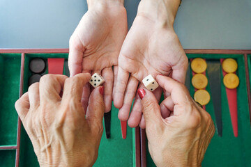 Hands holding dice over a backgammon board ready to play