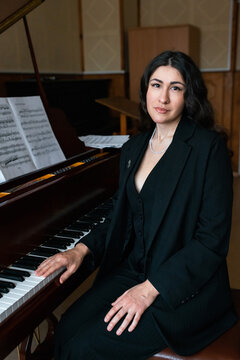 Pianist in black attire sitting beside grand piano keys