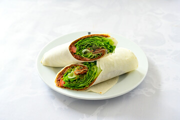 Cig kofte (raw meatball) with lettuce, tomato, pickle and lemon, hot Chee kofta. Turkish local raw food concept.Table scene of assorted take out or delivery foods. Doritoslu duble cig kofte durum.