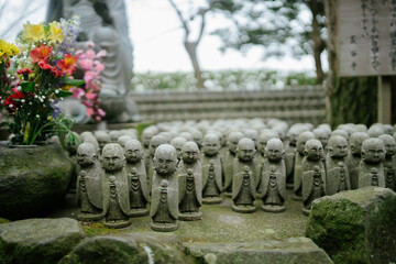A group of small, weathered stone Jizo statues stand in rows, creating a serene and spiritual scene. Kamakura, Japan