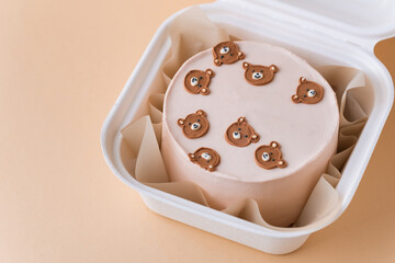 Little birthday bento cake with pink cream cheese frosting in a gift box decorated with cute cream teddy bear faces. Birthday cake for a girl on the beige pastel background