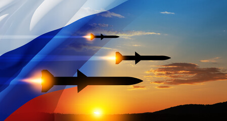 Fired missiles fly to the target. Missiles at the sky at sunset with Russian flag.