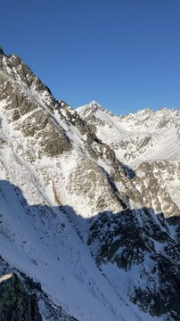 Predne Solisko, High Tatras, Slovakia. Winter landscape with mountains  and signboard marking top of peak and summit.  Sunny blue sky above clouds, temperature inversion. Vertical panning video.