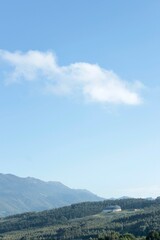 Fototapeta premium Tranquil Landscape Featuring Rolling Green Hills, Dense Forests, a Distant Dome-Shaped Building, and an Expansive Sky. With Blank Space for Text