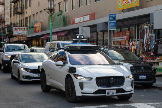San Francisco, CA, USA - Nov 24, 2024: Waymo's robotaxi navigates its way on the busy narrow streets in San Francisco's Chinatown. Waymo One is Alphabet's public, fully autonomous ride-hailing service