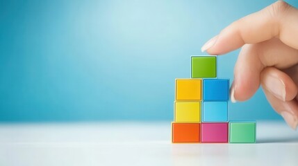 Colorful Building Blocks Stacked on Surface with Hand Placing Top Piece