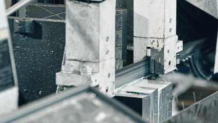Automated bandsaw cutting metal profiles with coolant flowing in a bustling metalworking factory, highlighting intricate industrial manufacturing processes and advanced engineering technology