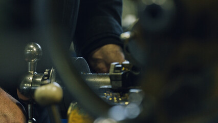 Close up of a metalworker's hands skillfully operating a lathe machine, creating precision metal parts in a factory workshop, showcasing industrial manufacturing processes