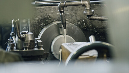 Obraz premium Close up view of cutting fluid being poured onto a metal piece during machining on an industrial lathe, generating swarf and ensuring optimal cooling and lubrication for precision work