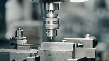 Close up of a drill press making a precise hole in a metal workpiece, showcasing the precision and automation of modern manufacturing processes in metalworking industry