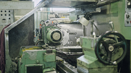 Metalworking cnc milling machine cutting a metal workpiece in a factory workshop, producing metal shavings during a high precision automated machining process