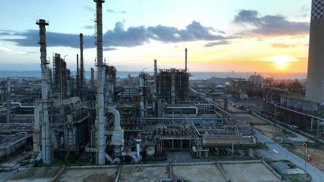 Aerial view of oil refinery plant at sunset. Drone shot. Smoking chimneys of the factory. Chimneys of chemical plant at sunrise pollute the environment