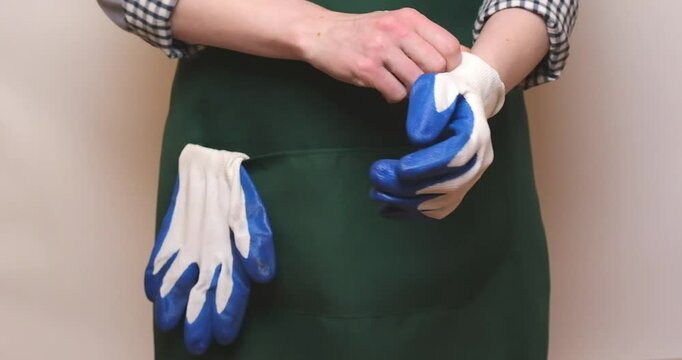 female gardener in work clothes puts on protective gloves to work in the garden. Preparing to work in the garden or flower shop.