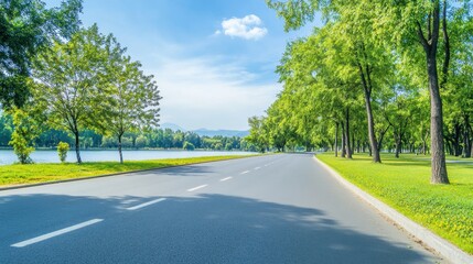 Fototapeta premium Serene Empty Road Surrounded by Lush Green Trees and Calm Water Reflection