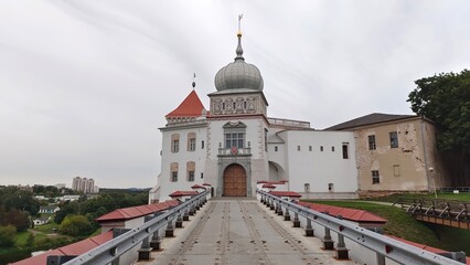 Naklejka premium The 11th century castle with towers was built of stone and red brick on a high hill above the town. It is currently being restored A bridge with a metal fence leads to the castle Cloudy summer weather
