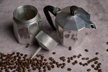 Disassembled geyser coffee maker moka machine parts. Scattered fresh aromatic coffee beans around. Gray concrete background. Preparation to making coffee