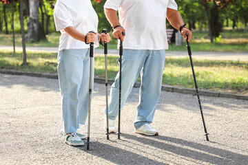 Mature woman and man training with walking poles in park, closeup