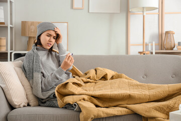Sick young woman measuring temperature  at home