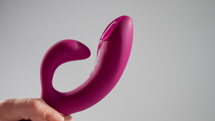 Lube pouring on pink dildo on white background. 