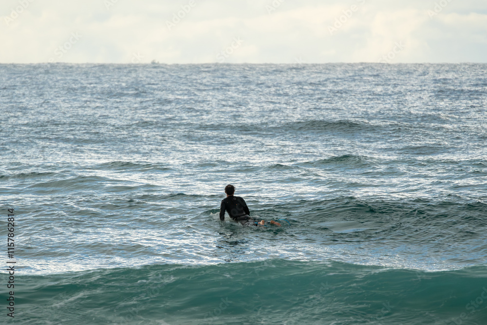 Canvas Prints Surfer in the ocean, seen from behind, waits patiently for a wave to ride