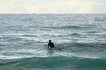Surfer ocean from behind waits patiently wave