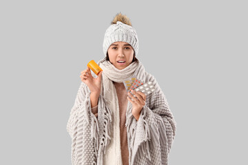 Sick young woman with pills on grey background