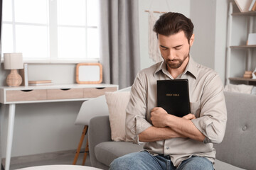 Religious man with Bible praying at  home