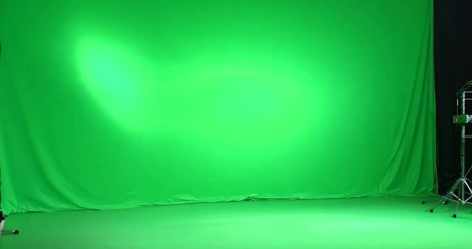 A seamless green screen in a professional video studio with no shadows or creases,