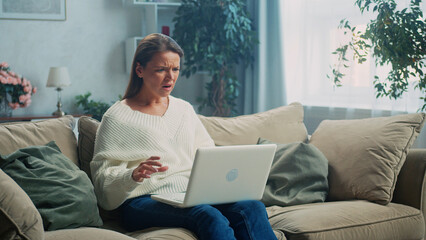 Stunned mature woman looking at laptop screen with grimace, reading bad news in email or social...