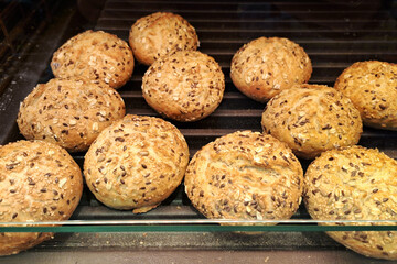 Fresh sesame Kaiser rolls on a bakery shelf. Golden brown buns topped with sesame seeds. Crisp and freshly baked rolls for breakfast or sandwiches. Bakery display of classic bread rolls.