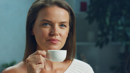 Beautiful woman savors a moment of peace as she sips coffee from a white cup in the comfort of her...