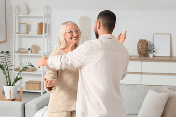 Young man with his mother opening arms for hug at home