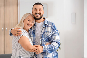 Happy young man hugging his mother at home