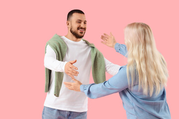 Young man with his mother opening arms for hug on pink background