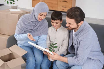 Happy Muslim family with photo frame sitting in room on moving day