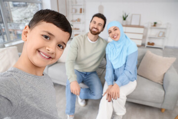 Fototapeta premium Happy Muslim boy with his parents taking selfie at home, closeup