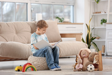 Cute little boy reading story with toys at home