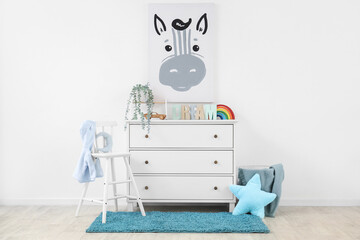 Interior of nursery with commode, chair and picture
