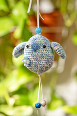 A small, blue crocheted bird ornament accented with dainty white and blue beads, suspended...