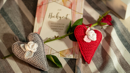 Two beautifully crocheted hearts with flower details are laid beside a wedding card, exuding romantic and celebratory vibes for a special occasion or gift.