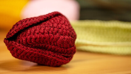 A crochet red flower bud, featuring meticulous detailing, is placed on a wooden surface, showcasing artistic craftsmanship and a touch of nature's beauty.