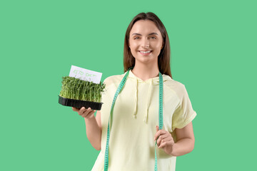 Young woman holding micro green with text KETO DIET on color background